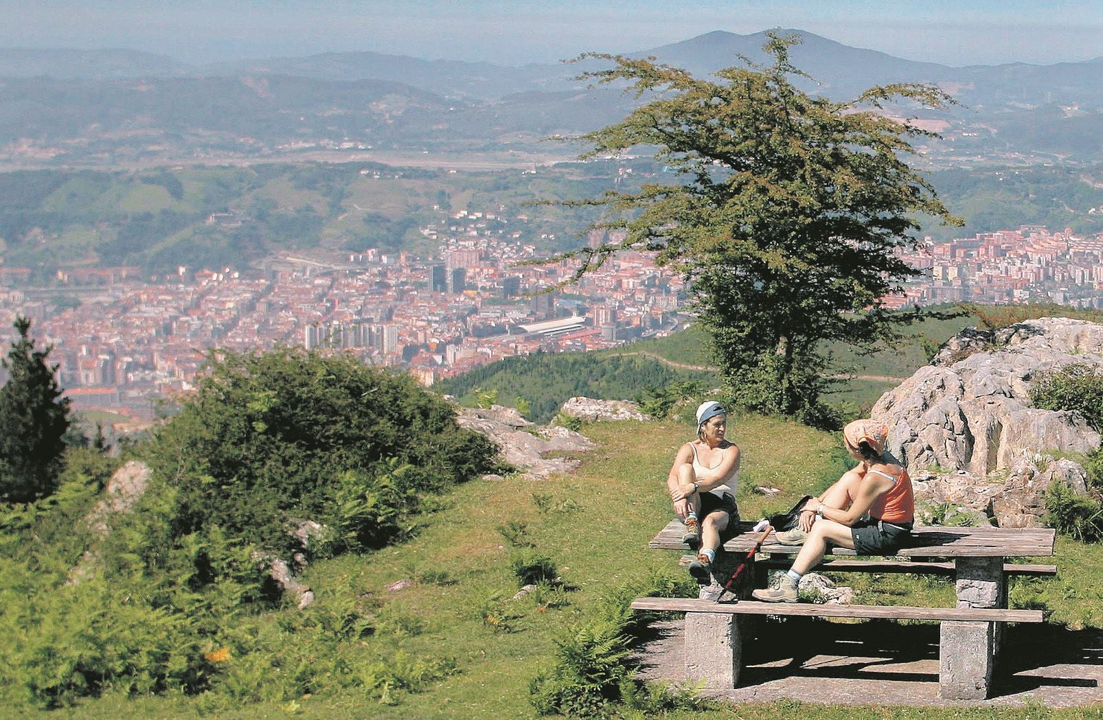 Dos mujeres descansan en el monte Pagasarri con Bilbao a sus pies.