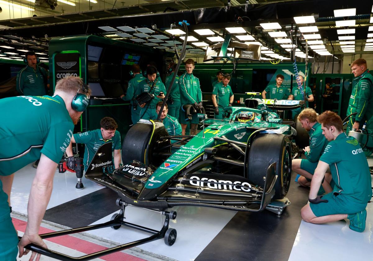 Los mecánicos de Aston Martin elevan el monoplaza de Fernando Alonso