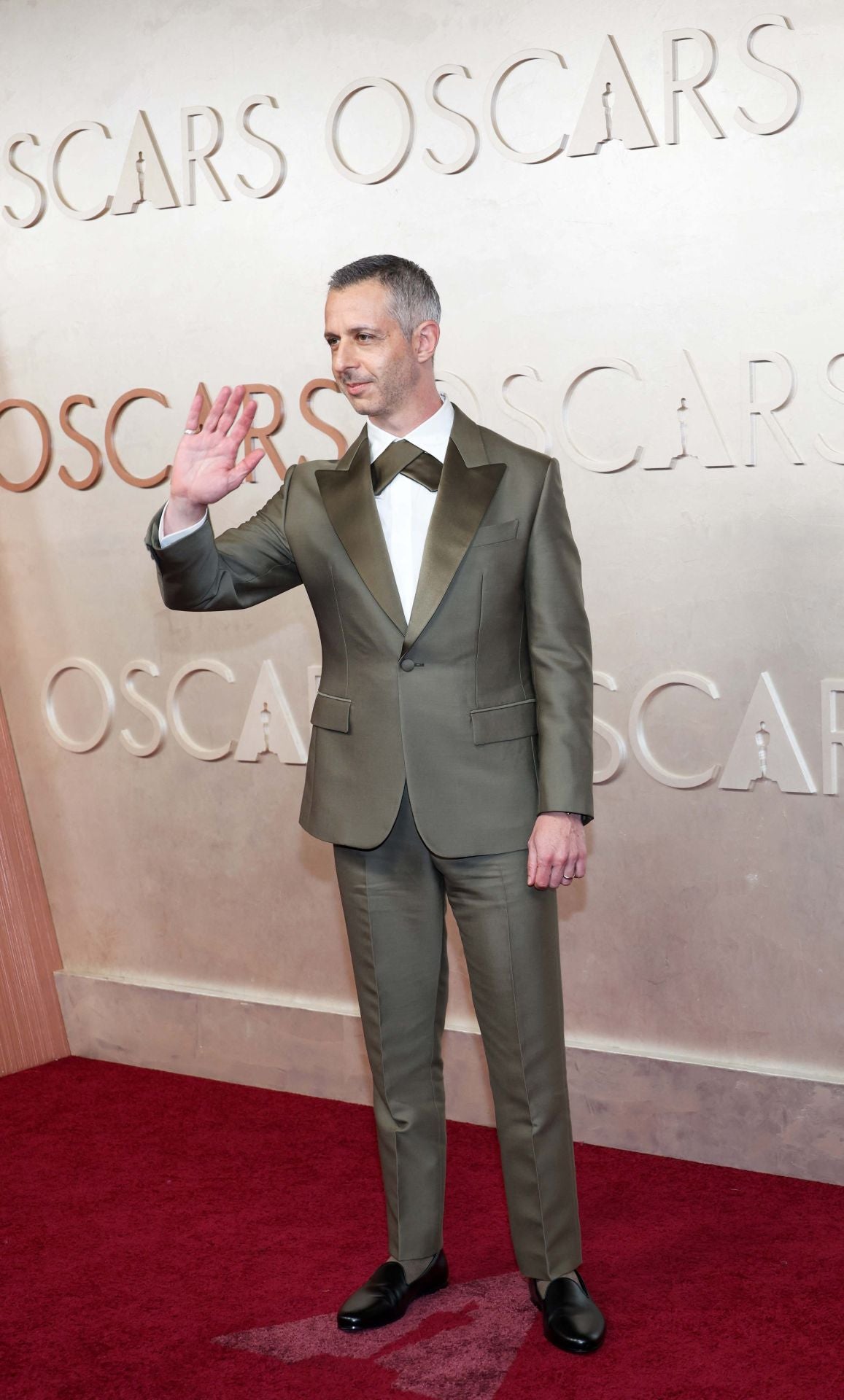 Original y elegante el look de Jeremy Strong, con traje en verde militar y un sorprendente detalle en el cuello al estilo pajarita de Loro Piano.
