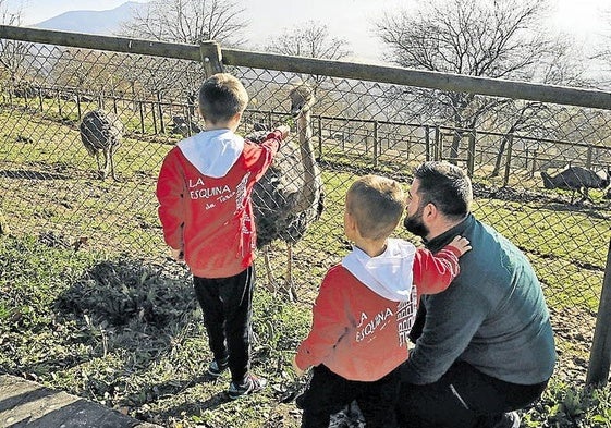 Unos niños tratan de atraer la atención de un emú en las instalaciones del Karpin.