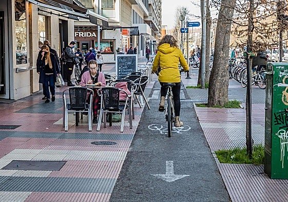 Una bicileta transita por el bidegorri de la Avenida junto a una terraza de hostelería.