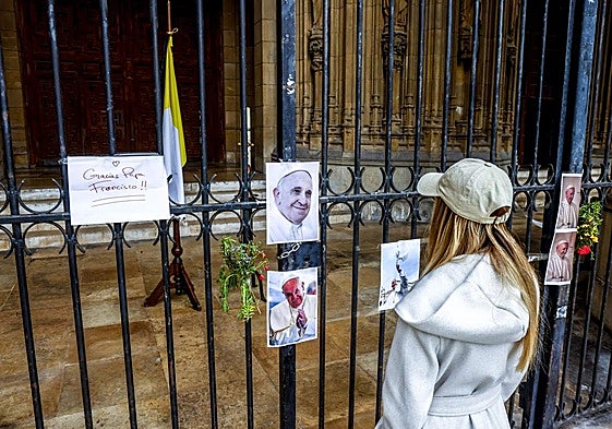 Una joven observa algunas de las fotos y carteles colocados sobre la verja de la Catedral Nueva de Vitoria.