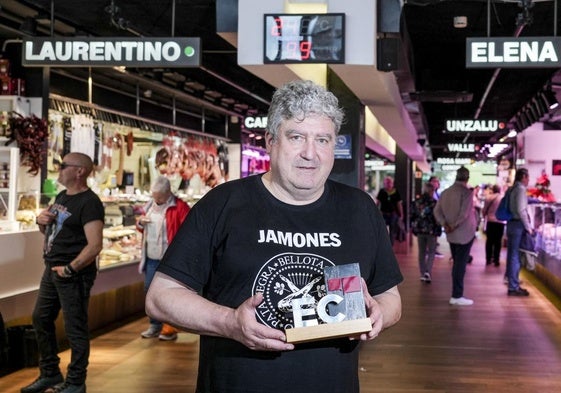 Txomin Gómez Zubia sostiene el premio del Alavés del Mes entre los puestos del mercado de Abastos.
