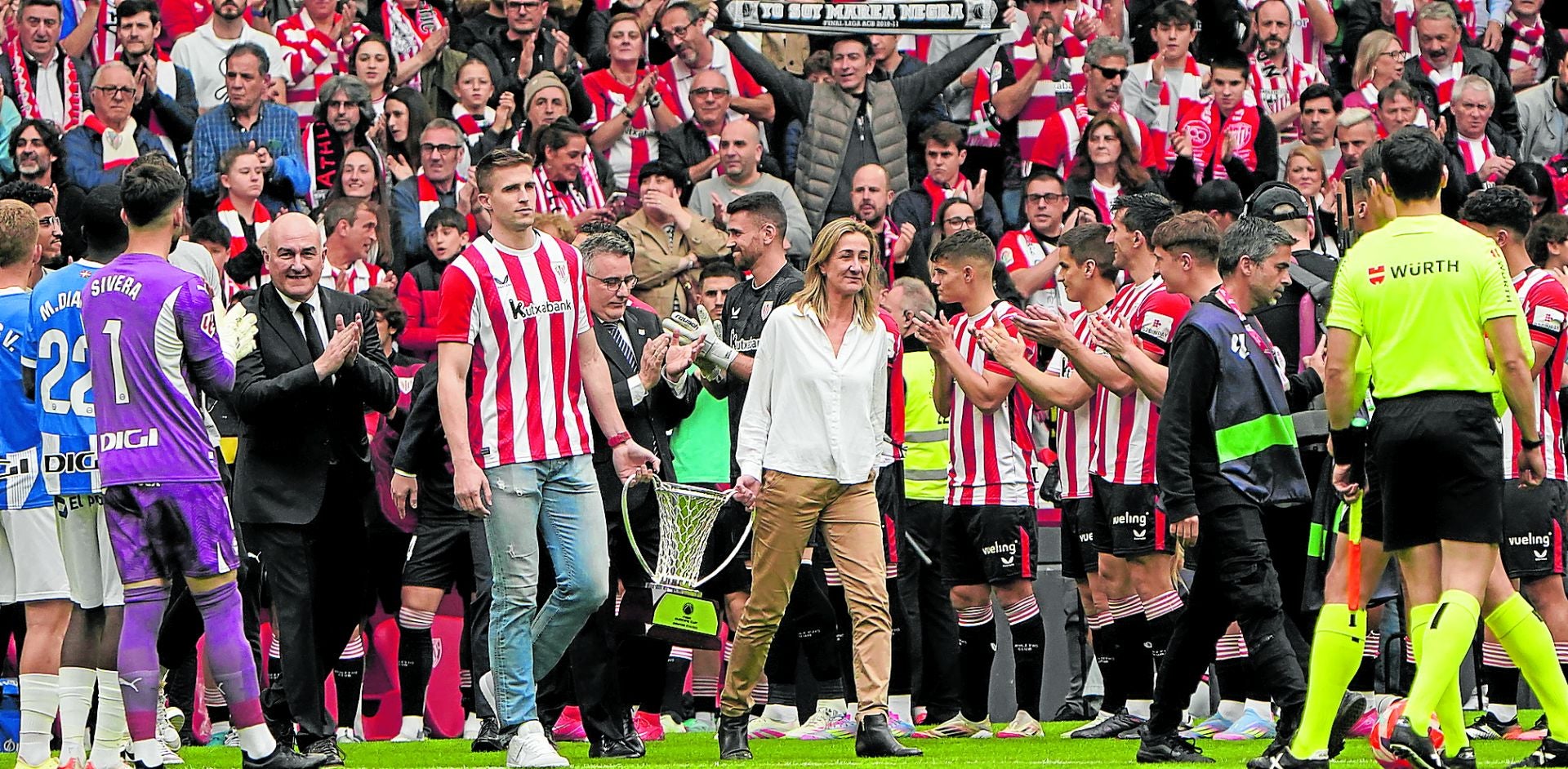 Xavi Rabaseda e Isabel Iturbe, portando la copa de campeones de la Europe Cup. encabezan la salida del Surne Bilbao Basket al centro de San Mamés.