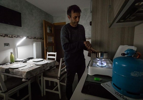Ricardo cocina en un hornillo de gas con la iluminación de un flexo con batería