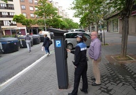 Un vigilante de OTA explica cómo funciona un parquímetro en Adurza