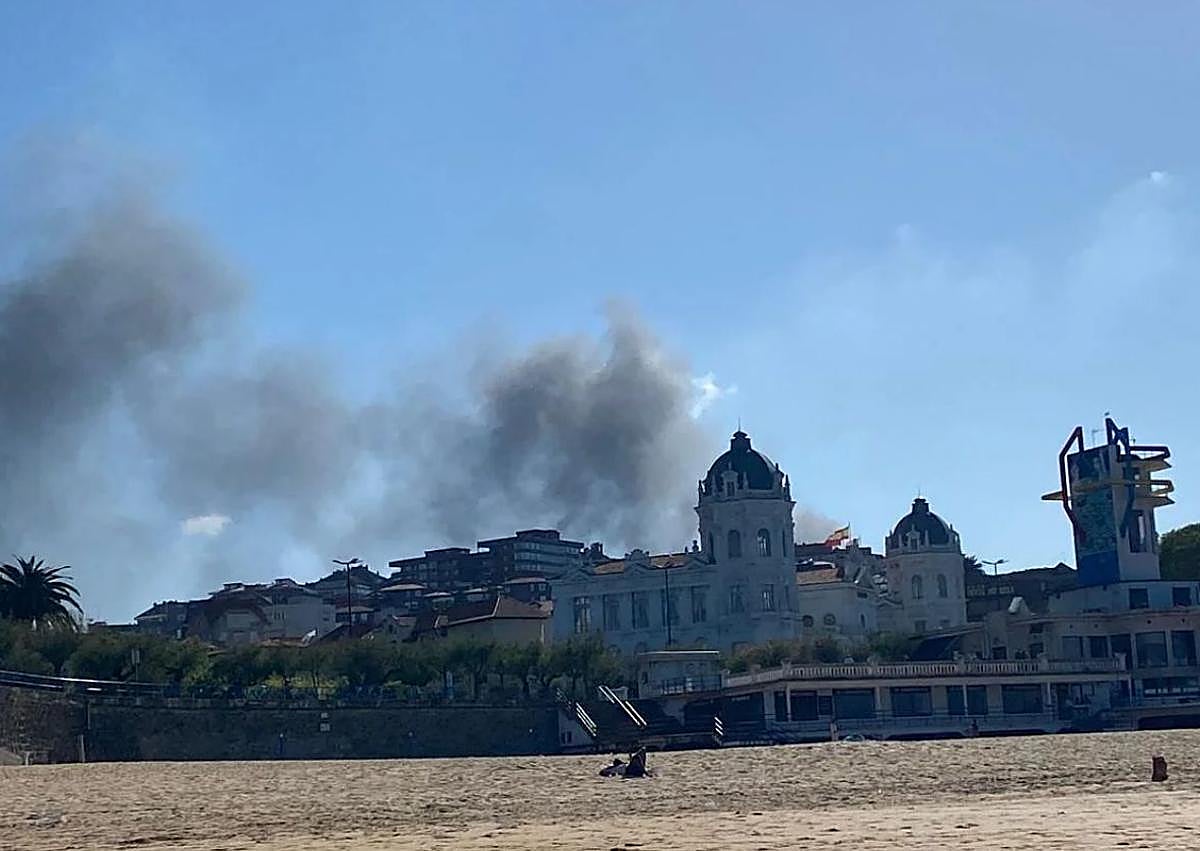Imagen secundaria 1 - Arriba, momento en el que los bomberos han conseguido controlar el incendio. Abajo, la columna de humo vista desde los Jardines de Pereda y desde El Sardinero.