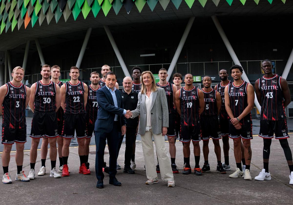 Xabier Sagredo, presidente ejecutivo de BBK, e Isabel Iturbe, presidenta del Bilbao Basket, se estrechan la mano frente a la plantilla, con Miribilla a sus espaldas.