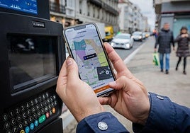 Una persona paga la OTA a traves de la aplicación móvil, en la calle Florida de Vitoria.