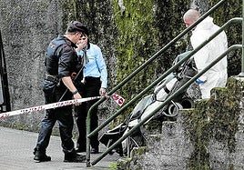 Ertzainas y responsables de la investigación trasladan uno de los cadáveres.