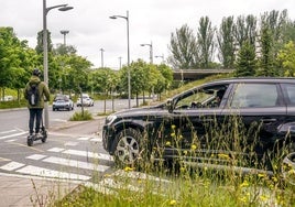 Un coche frena en un paso de cebra por donde pasa un patinete.