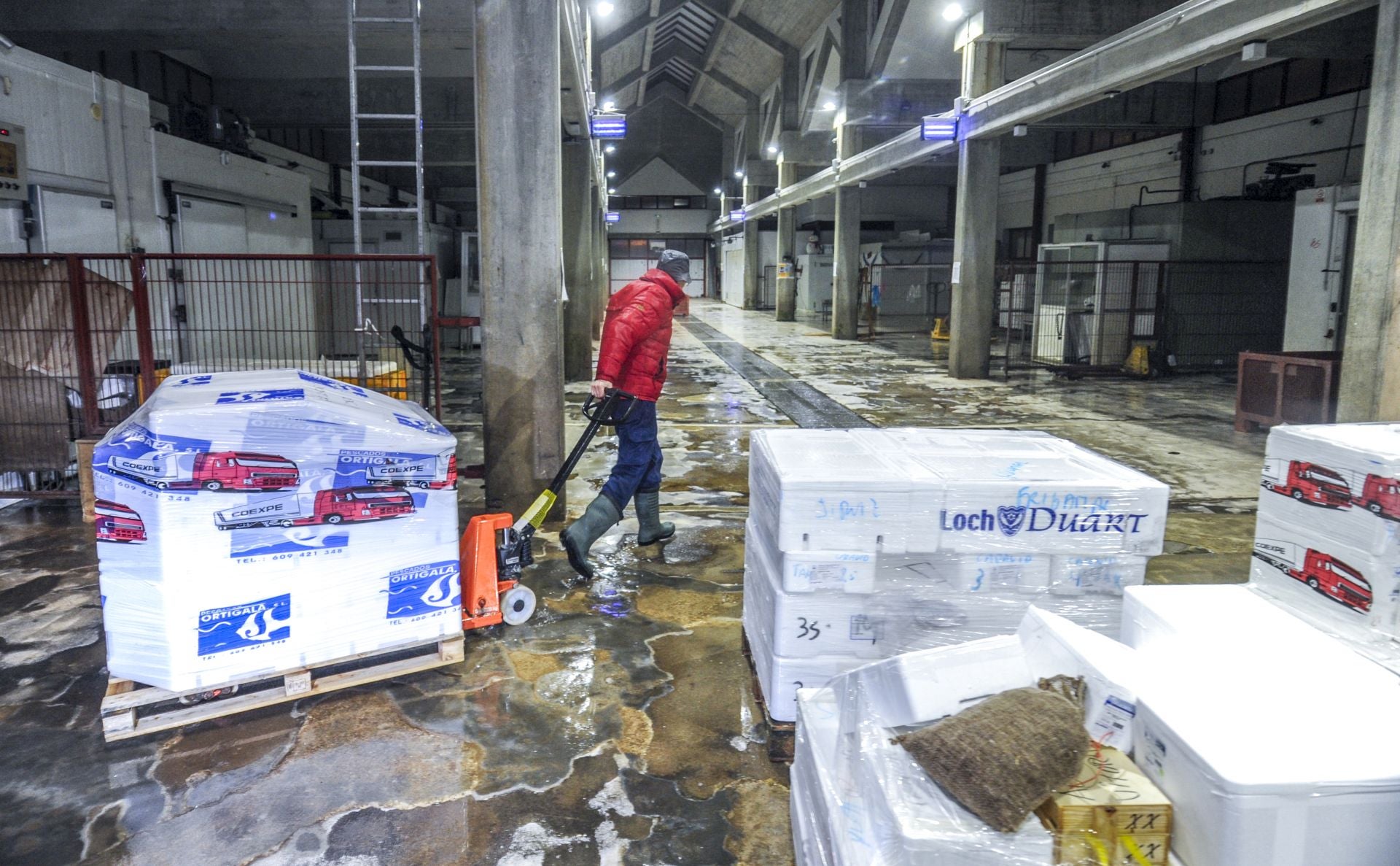 Un pescatero se lleva unas cajas a su camión.
