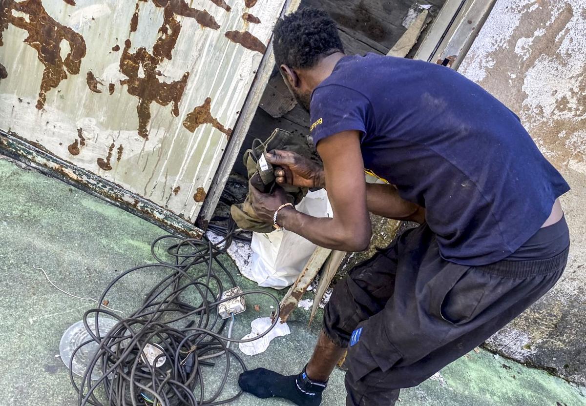Imagen principal - Mamadou, con la pulsera de localización, recoge cable. Estado actual de una oficina de URSSA. Otro okupa preparado para salir con un carrito de supermercado lleno de material sustraído.