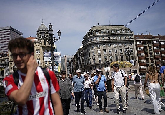 Bilbaínosy turistas se entremezclan en el puente del Arenal.