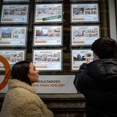 Jóvenes observan los anuncios de una inmobiliaria en Bilbao.