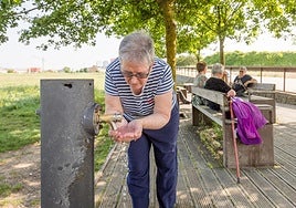 Una mujer se refresca en una fuente de Salburua.