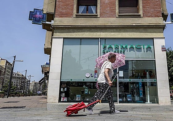 Una mujer se protege con un paraguas ante los 35 grados que marcaban estos termómetros al mediodía.