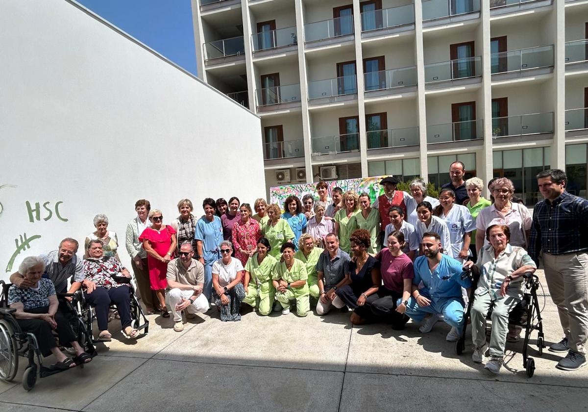 Los usuarios de la residencia se sacaron una foto de familia junto con los cuidadores y el mural realizado.