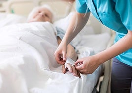 Una sanitaria asiste a una anciana durante su ingreso hospitalario.