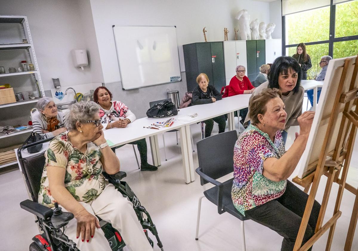 Sesión de pintura. Judith remata el lienzo con los consejos de Virginia. El resto observa la creación y charla.