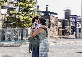 Dos trabajadoras de LEA se abrazan ante la planta incendiada.