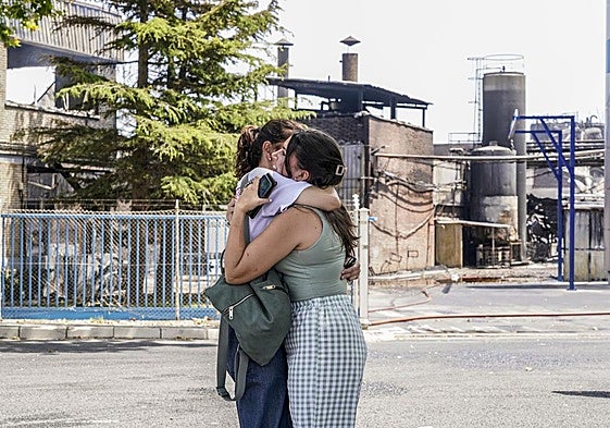 Dos trabajadoras de LEA se abrazan ante la planta incendiada.