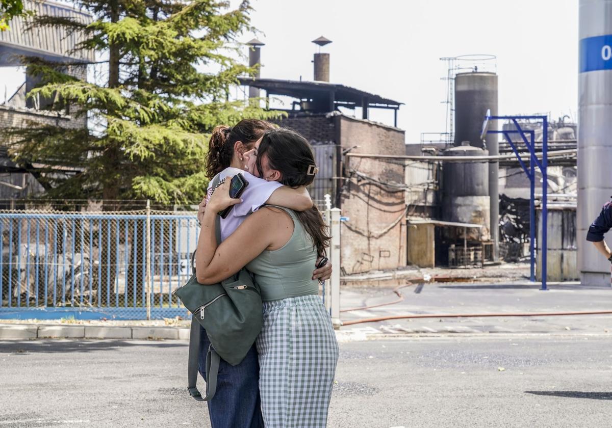 Dos trabajadoras de LEA se abrazan ante la planta incendiada.
