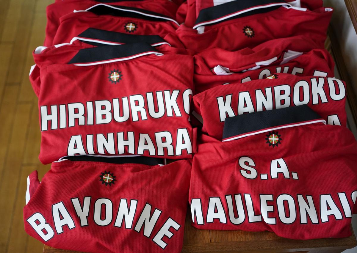 Imagen secundaria 1 - Arriba, el coordinador de captación del Athletic en Iparralde, Alexandre Pollet. A la izquierda, camisetas que fueron regaladas a cada club convenido. A la derecha, Uriarte con Etchegaray.