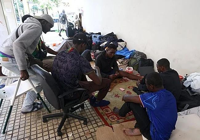 Un grupo de malienses mata el tiempo jugando a las cartas en los soportales donde están asentados en la plaza Cofradías Donostiarras