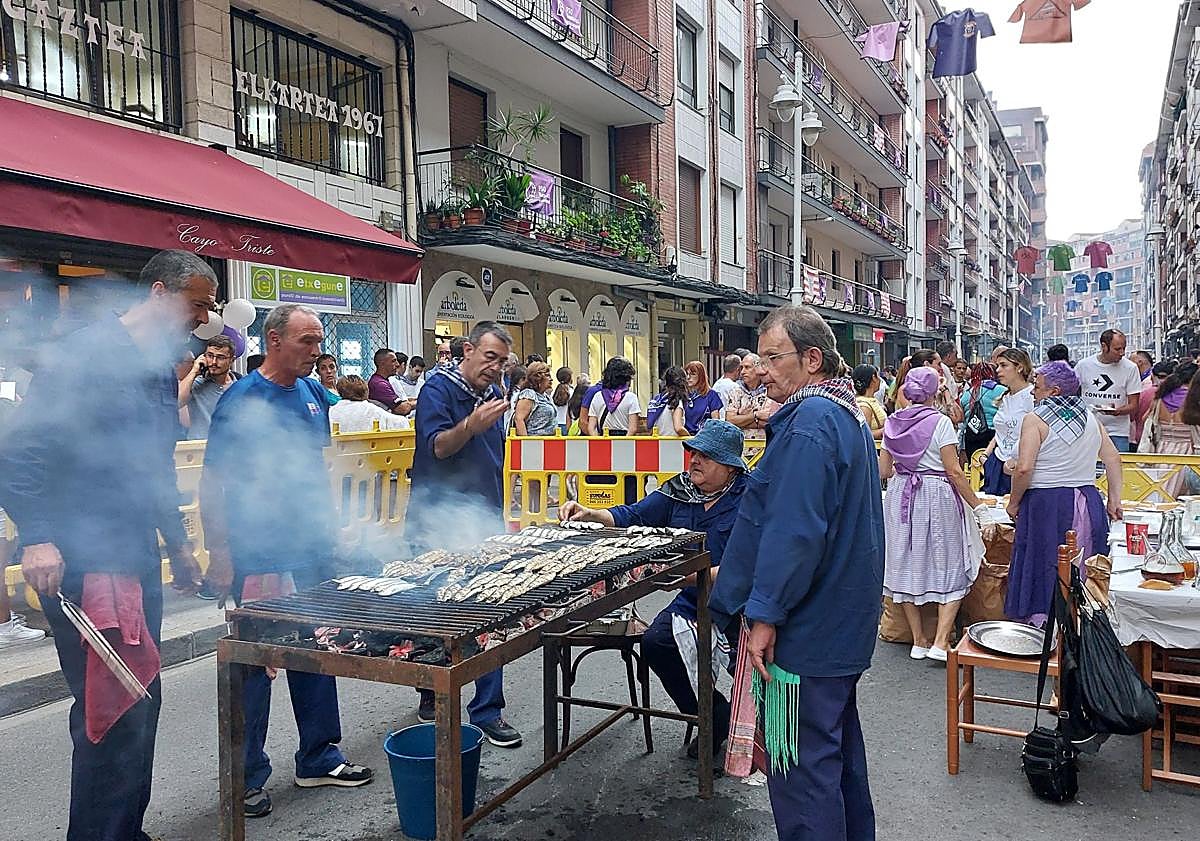 Imagen principal - Las pailas abarrotaron las calles Itsasalde y Juan XXI. Abajo, Jina Zamarreño y Piedad Villacorta antes de degustar las sardinas.