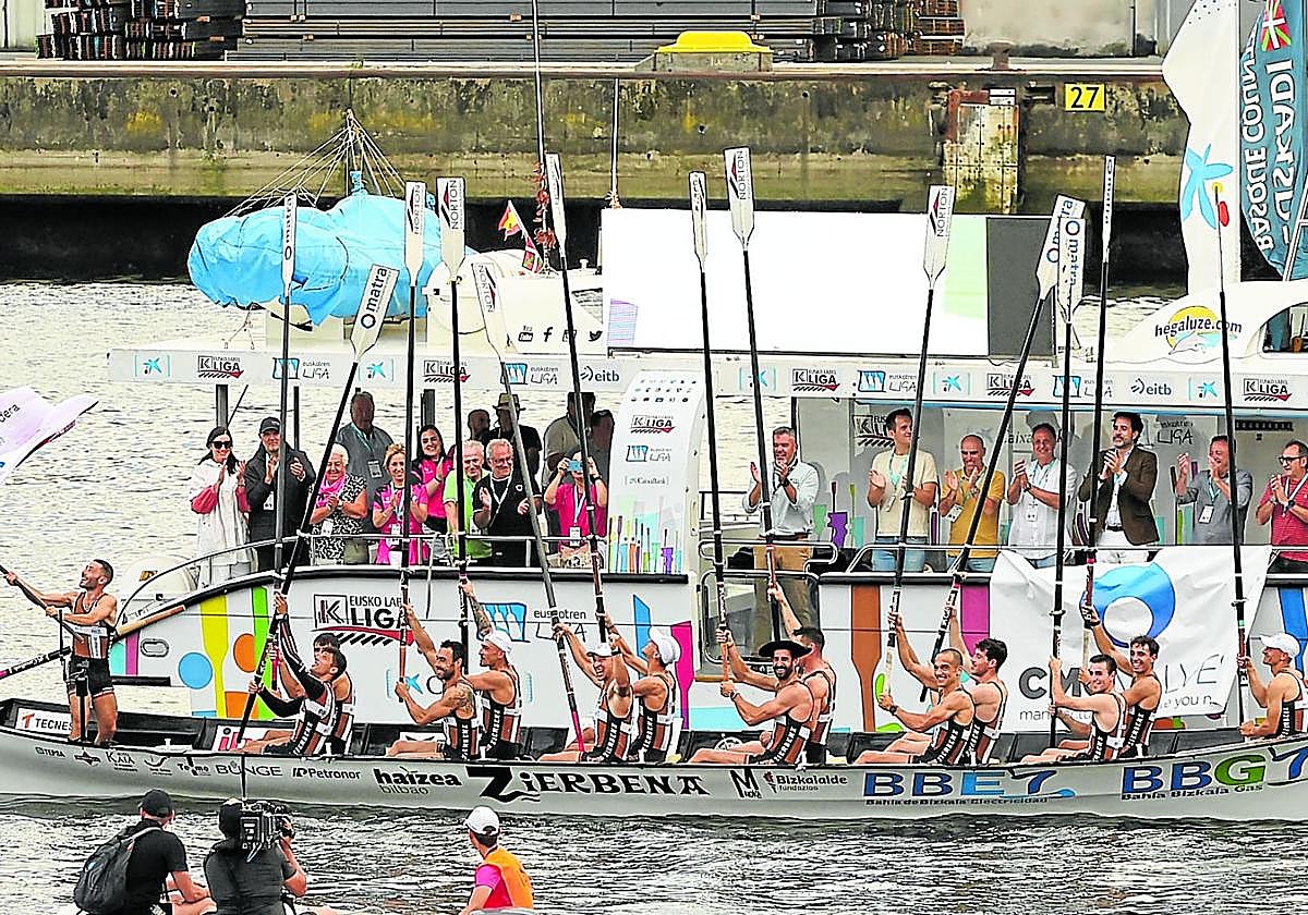Los remeros de Zierbena saludan a la afición con los remos en alto, mientras su patrón, Aitor Lazkano, ondea la primera bandera de la temporada conquistada en Pasaia