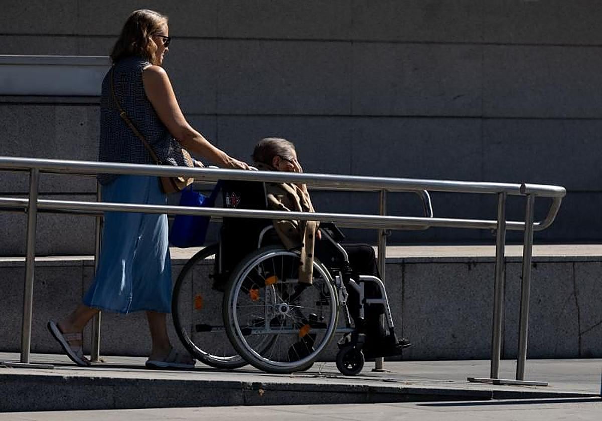 Una mujer pasea a una señora dependiente