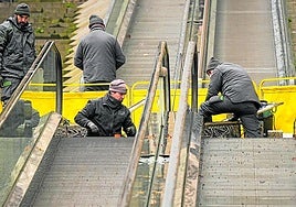 Unos operarios arreglan las escaleras mecánicas en un cantçon del Casco Viejo