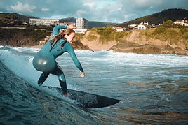 Una mujer surfea sobre su tabla una ola en la playa de Bakio.