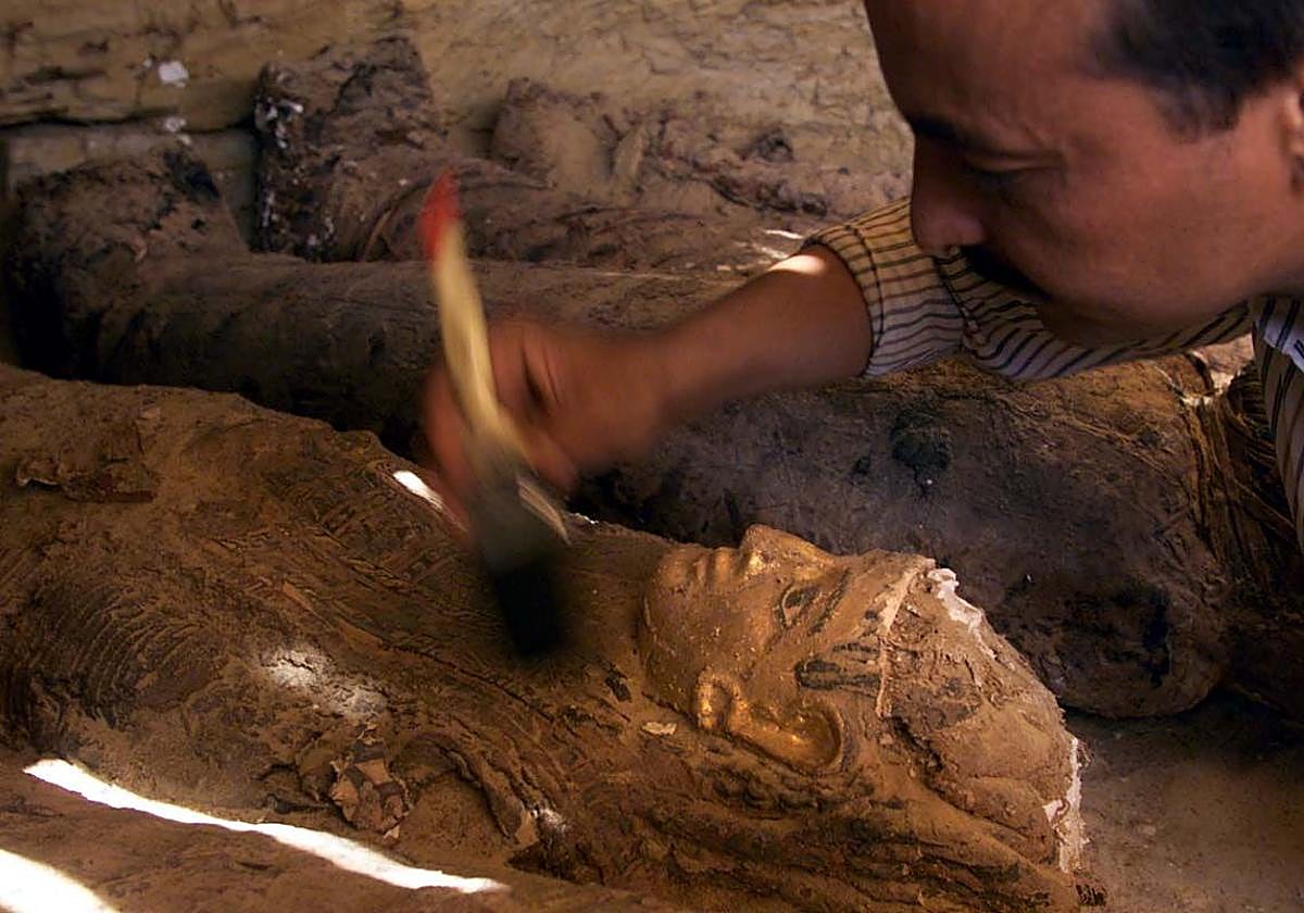 Operario egipcio limpia una momia de casi dos mil años que ha sido descubierta en el Valle de las Momias de Oro, en el Oasis Bahariya.