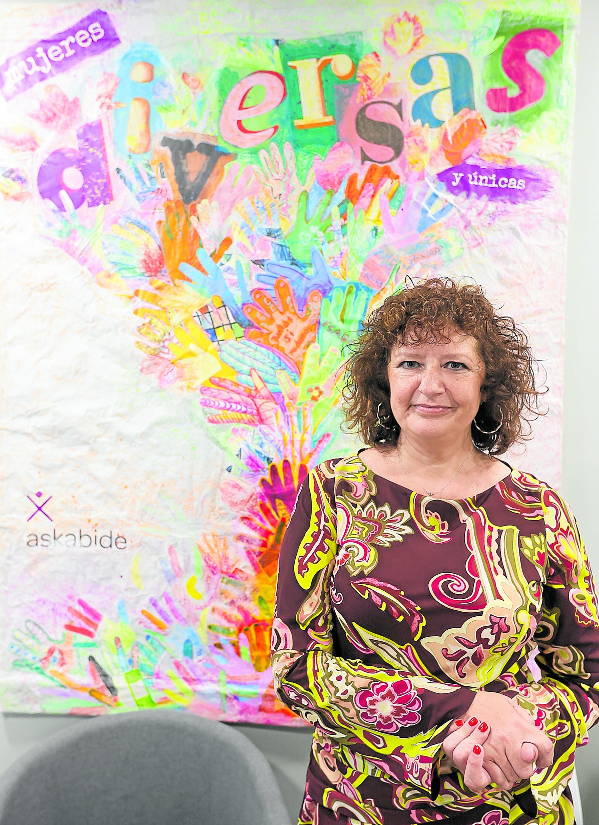 Arias, junto a un mural elaborado por las usuarias de la entidad, que ofrece diferentes servicios.