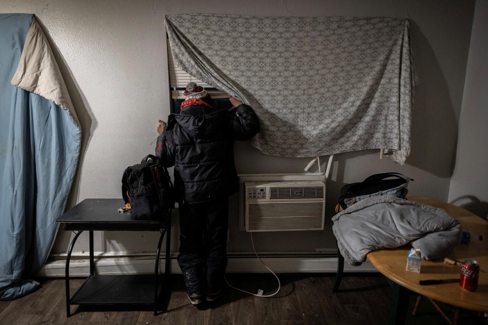 Un hombre venezolano mira por la ventana en busca de señales de agentes federales después de escuchar informes de que el Servicio de Inmigración y Control de Aduanas de Estados Unidos vendrá a detener inmigrantes para su deportación en Aurora, Colorado.
