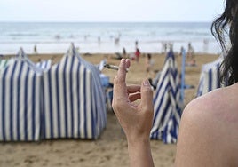 Una mujer fuma un cigarro en la playa de Zarautz, una práctica que estará prohibida dede el próximo verano.