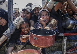 Palestinos esperan recibir comida donada en la ciudad de Gaza.