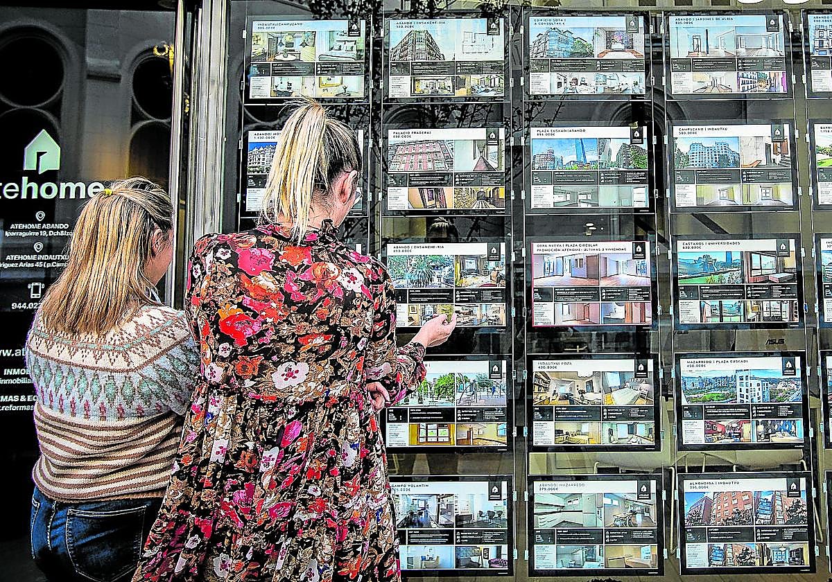 Dos mujeres observan el escaparate de una inmobiliaria. Estas han canalizado en vivienda usada ocho de cada diez ventas.