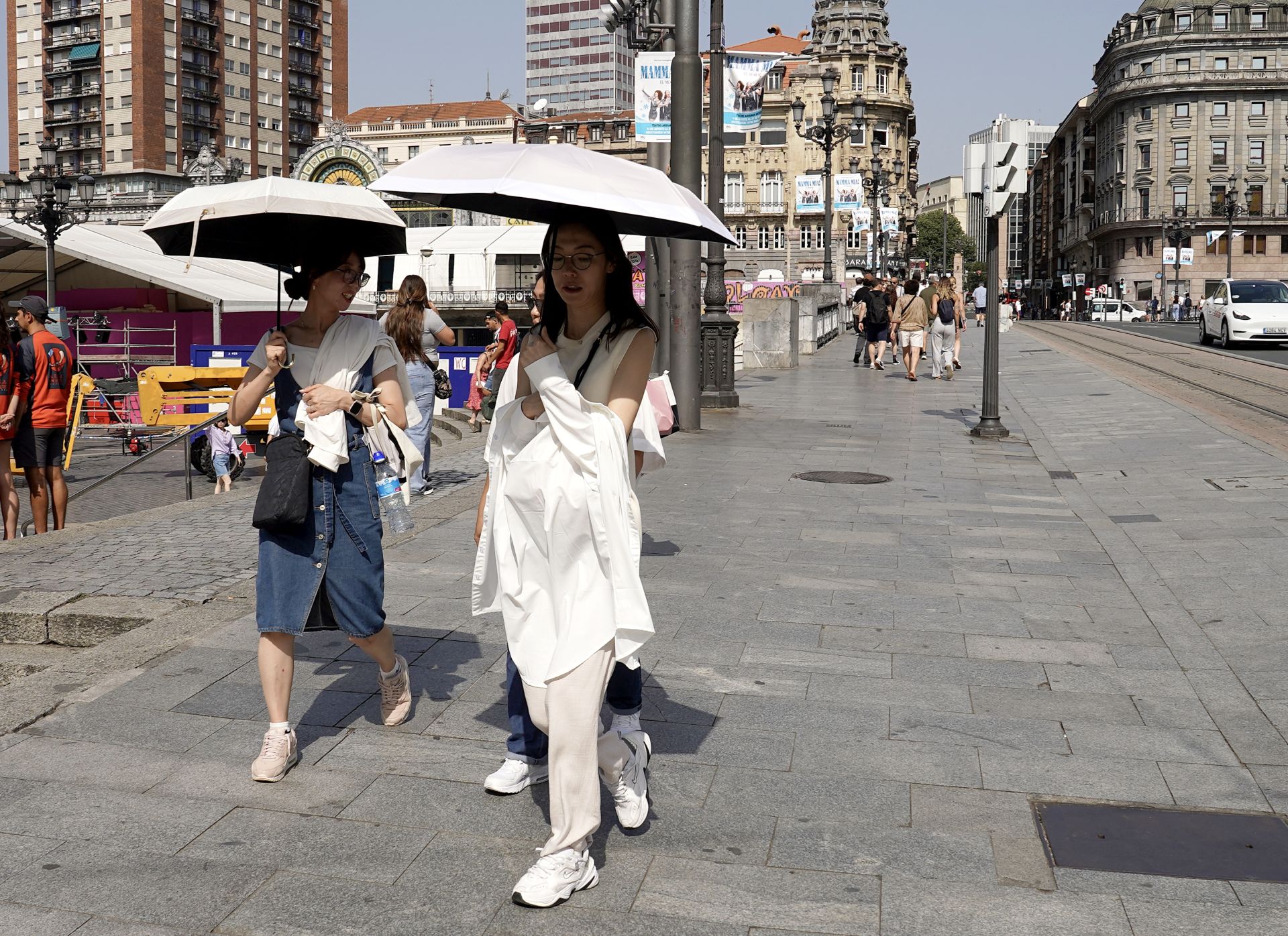 Varias mujeres se protegen del sol con un paraguas en el puente del Arenal.