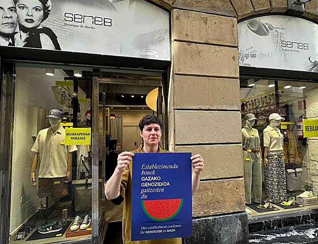 Cristina Cendoya, propietaria de la tienda Serie B, sostiene el cartel frente a su escaparate.