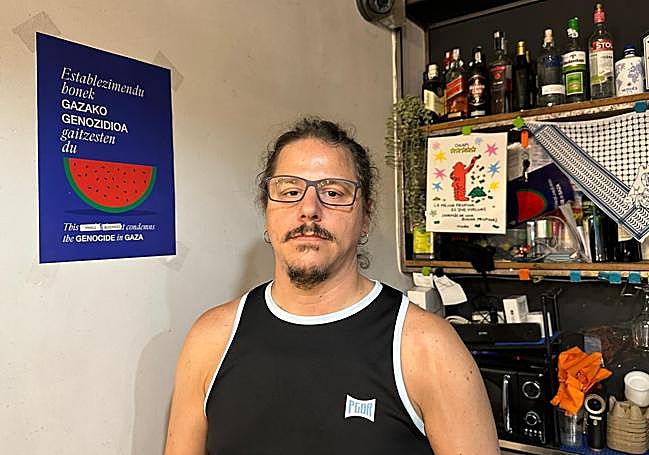 Agus Sanz, propietario de Café Obrador Okapi, posa delante del cartel que denuncia el genocidio en Gaza.