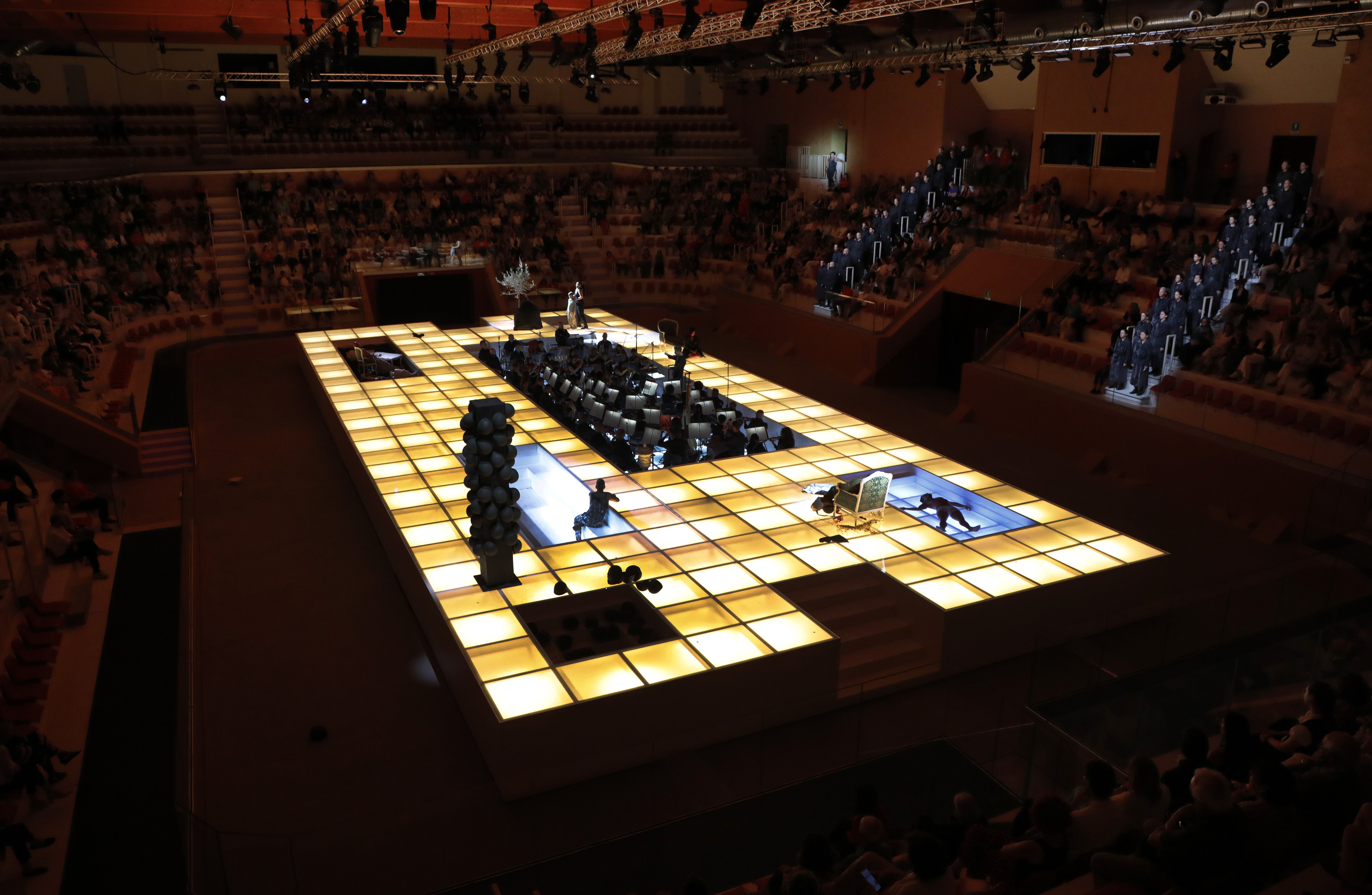 El escenario es una plataforma luminosa (de 30 metros de largo y 12 de ancho) con un foso en el centro que acoge la orquesta.
