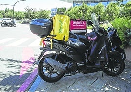 Una moto de Glovo aparcada en frente del centro comercial Garbera, donde opera Eroski.