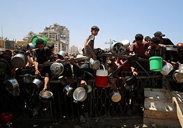 Palestinos esperan recibir comida de un comedor social, en medio de una crisis de hambre en Gaza.