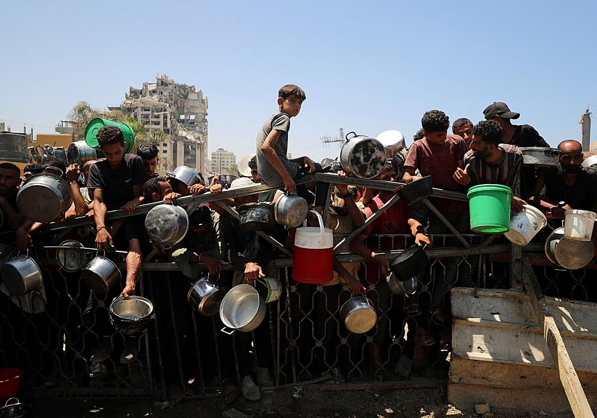 Palestinos esperan recibir comida de un comedor social, en medio de una crisis de hambre en Gaza.