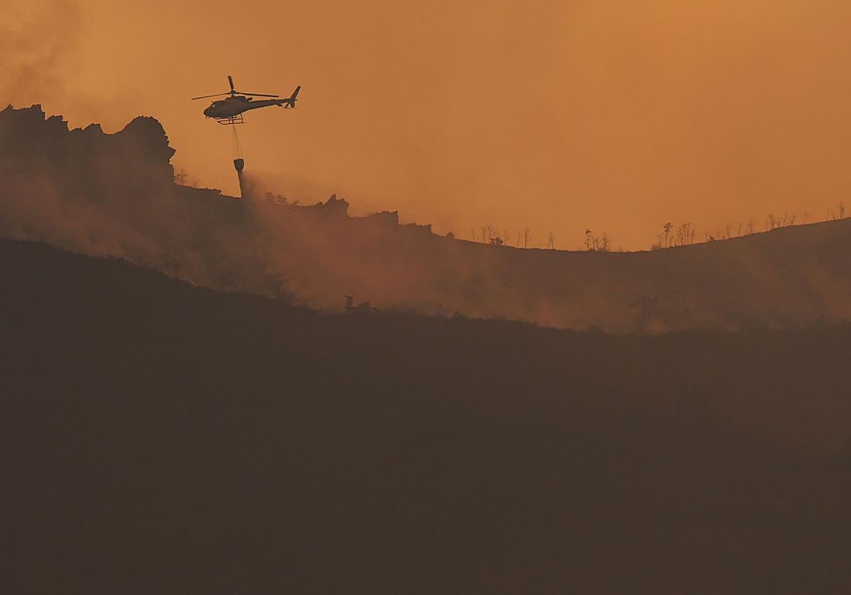 Un helicóptero de bomberos combate un incendio forestal en León.