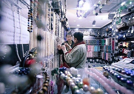 Hao atendiendo a una clienta en su comercio de Bilbao.