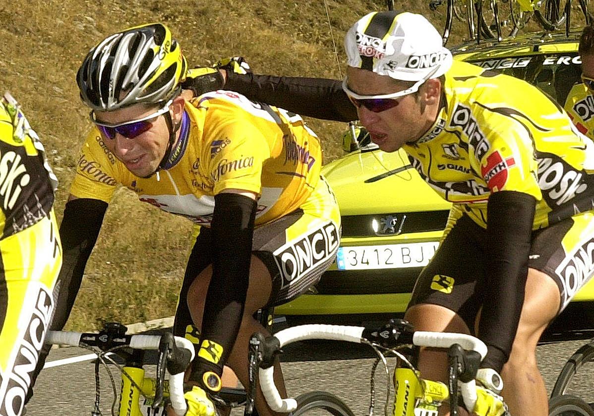 Carlos Sastre (d) anima a Joseba Beloki, que llora, durante el ascenso del puerto de Envalira (11ª etapa), al saber que ha perdido el maillot de líder de la Vuelta Ciclista a España 2001.